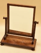 A NINETEENTH CENTURY MAHOGANY TOILET MIRROR on bun feet with bead rim and fluted supports, 56cms