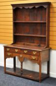 A MINIATURE OAK WELSH DRESSER having a closed rack above an arrangement of four drawers and one