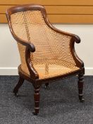 AN ANTIQUE MAHOGANY FRAMED CANE WORK CHAIR having carved terminals to the arms and on turned