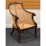 AN ANTIQUE MAHOGANY FRAMED CANE WORK CHAIR having carved terminals to the arms and on turned