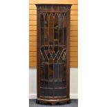 A BOW FRONTED STANDING CORNER CABINET having a single glazed door, geometrically divided and with