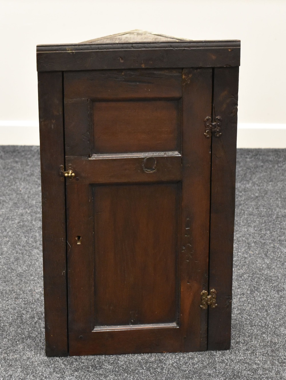 AN EARLY NINETEENTH CENTURY HANGING CORNER CUPBOARD of primitive form with single hinged door