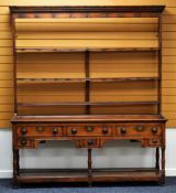 AN OAK WELSH DRESSER having an open rack above a base of three short drawers and three narrow deep