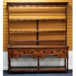 AN OAK WELSH DRESSER having an open rack above a base of three short drawers and three narrow deep