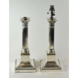 A PAIR OF SILVER LAMP-BASES of Classical architectural form with floral terminals over Corinthian