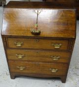 AN ANTIQUE OAK BUREAU having two long drawers, shorter drawer and sloped front with brass fittings