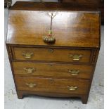 AN ANTIQUE OAK BUREAU having two long drawers, shorter drawer and sloped front with brass fittings