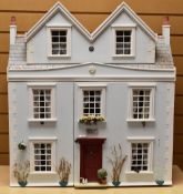 A HOME BUILT PAINTED DOLLS HOUSE in the form of an eight-window cottage with lightwood cabinet