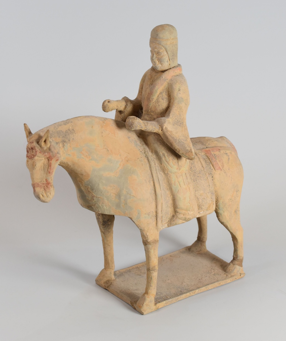 A CHINESE ARCHAIC TERRACOTTA TOMB-HORSEMAN standing on a rectangular base, 27cms high