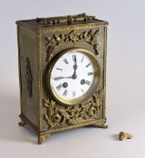 A BRASS ENCASED MANTEL CLOCK having a circular white dial bearing Roman numerals and handle to the