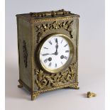 A BRASS ENCASED MANTEL CLOCK having a circular white dial bearing Roman numerals and handle to the