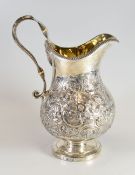 A GEORGIAN SILVER JUG with all round floral repousse work (possibly later), over a circular foot and