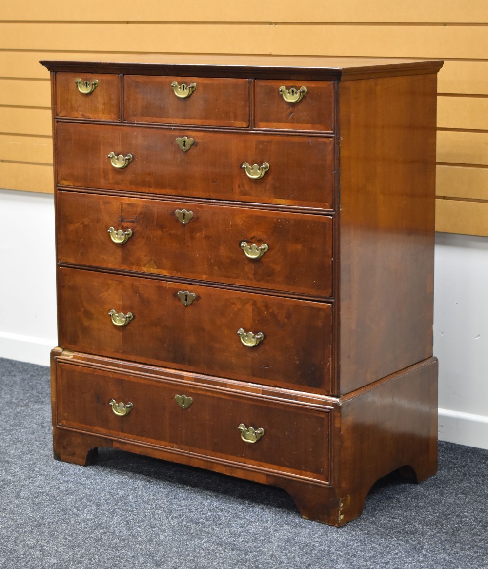 A GEORGE III WALNUT CHEST composed of four graduated long drawers and three short drawers with brass