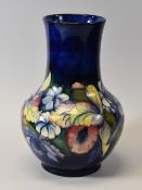 A MOORCROFT ONION-SHAPED VASE typically decorated with tube-lined Spring Flowers to a blue ground,