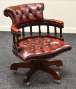 A REPRODUCTION CAPTAIN-STYLE OFFICE CHAIR with buttoned red leather upholstery