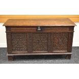 A LATE EIGHTEENTH CENTURY OAK BLANKET CHEST having a heavily carved panel facade, panelled sides and
