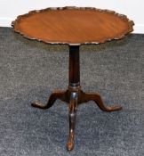 A TILT-TOP MAHOGANY TRIPOD TABLE having a wavy piecrust top and on carved supports