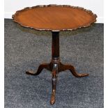 A TILT-TOP MAHOGANY TRIPOD TABLE having a wavy piecrust top and on carved supports