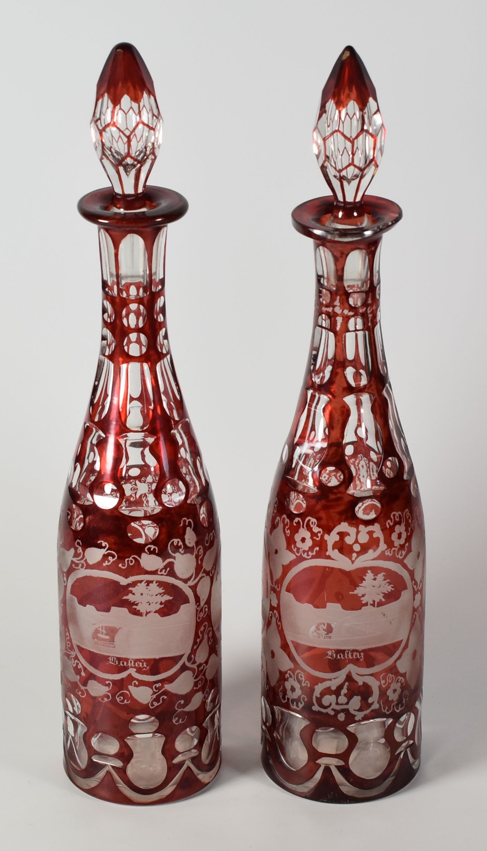 A PAIR OF GERMAN RUBY FLASH DECANTERS with stoppers and with opposing cartouches of etched buildings