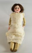 AN EDWARDIAN PORCELAIN HEAD DOLL having opening and closing eyes and with porcelain forearms and