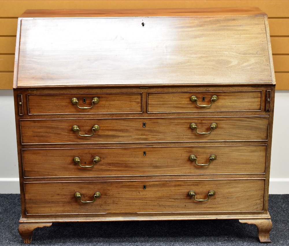 A GEORGIAN MAHOGANY BUREAU having four graduated long drawers and two short and with sloped hinge