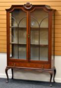 AN EDWARDIAN INLAID MAHOGANY CABINET standing on bow supports with base drawer and two shaped glazed