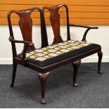 AN EDWARDIAN MAHOGANY ELBOW SOFA having carved and shaped backs and cabriole supports with floral