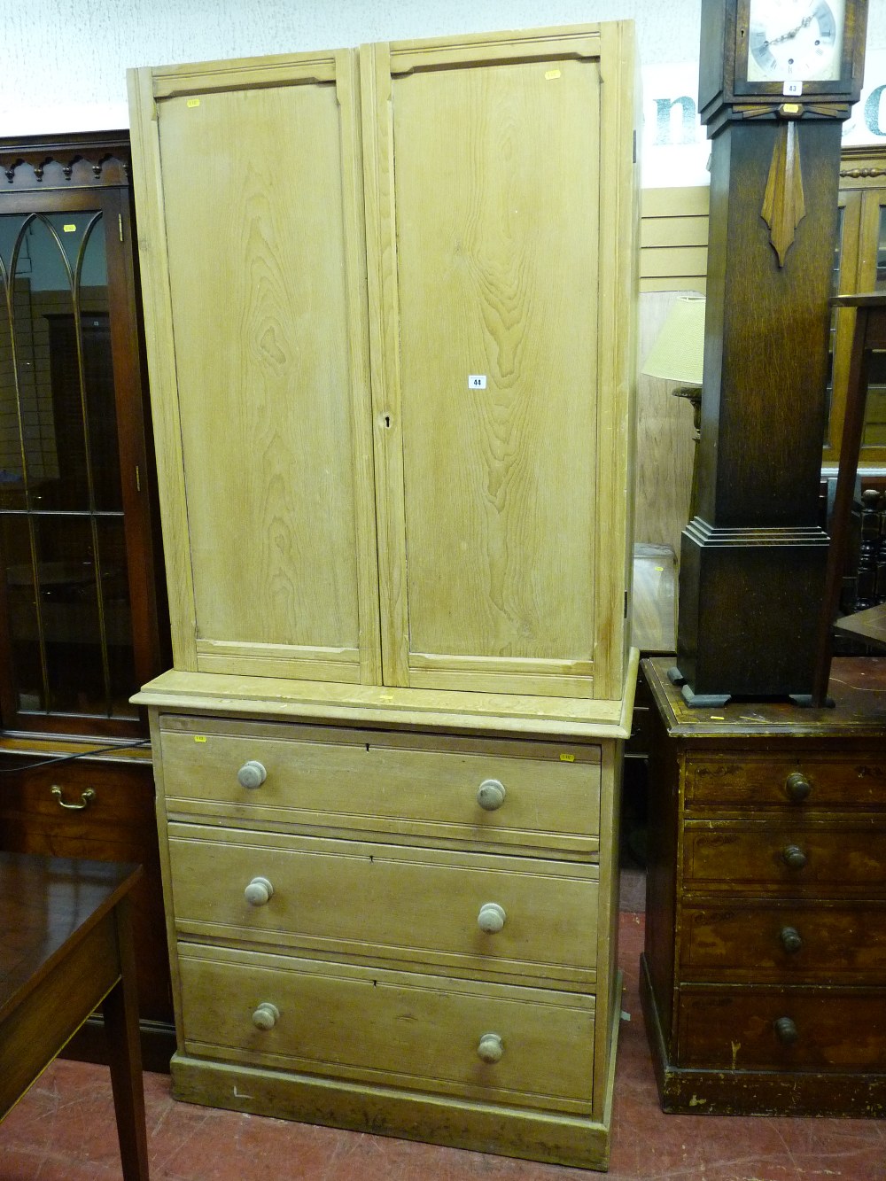 A VICTORIAN STRIPPED PINE TWO DOOR CUPBOARD on a chest of three long drawers with turned wooden