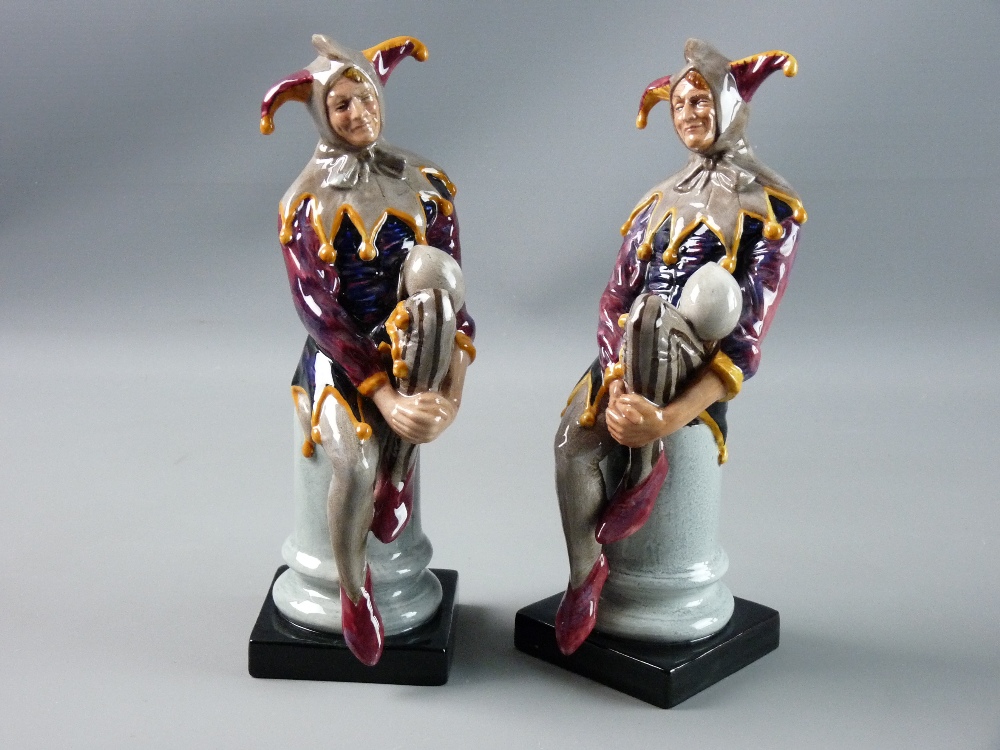 TWO ROYAL DOULTON FIGURINES titled 'The Jester', the figures in colourful costume seated on a