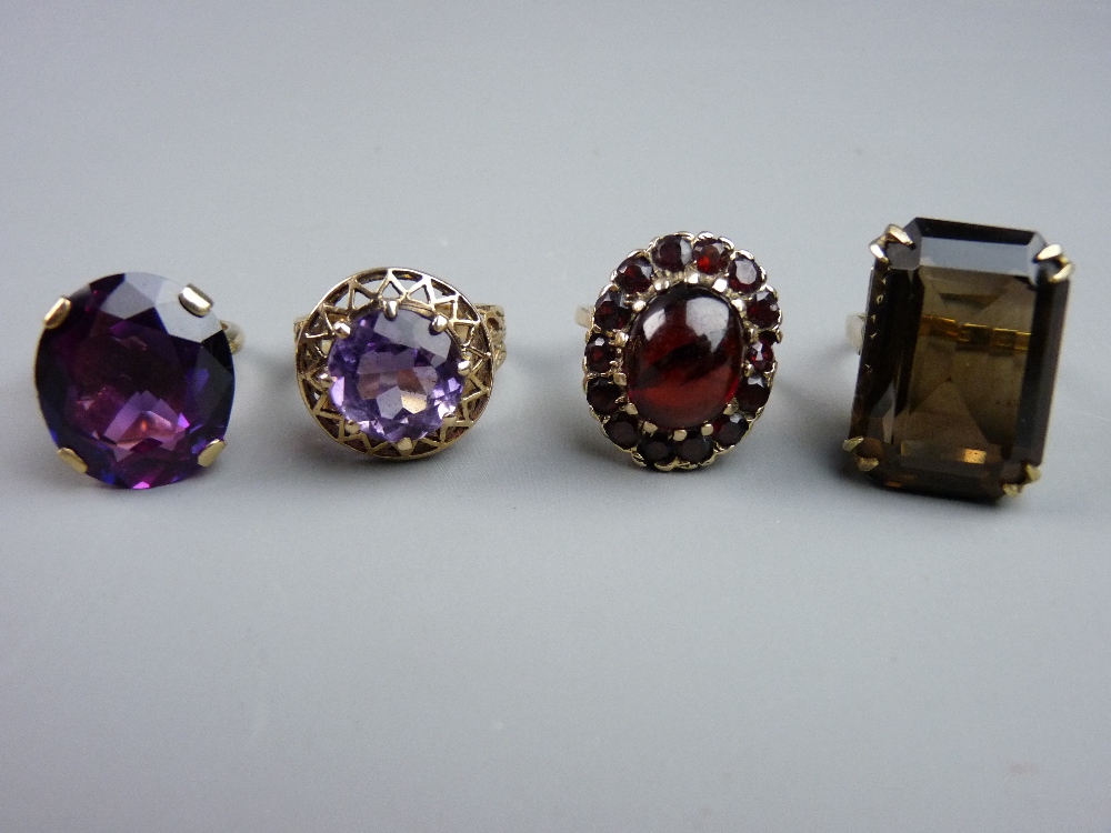 FOUR NINE CARAT GOLD DRESS RINGS, all with large smoky quartz, garnet and amethyst decoration, 26