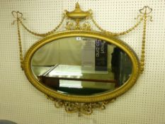 AN OVAL GILT FRAMED CLASSICAL STYLE WALL MIRROR with classical urn and garlands to the top and