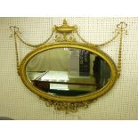 AN OVAL GILT FRAMED CLASSICAL STYLE WALL MIRROR with classical urn and garlands to the top and