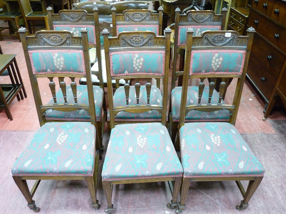 A SET OF SIX EDWARDIAN OAK TALLBACKED DINING CHAIRS, the top rails having garlanded decoration and a