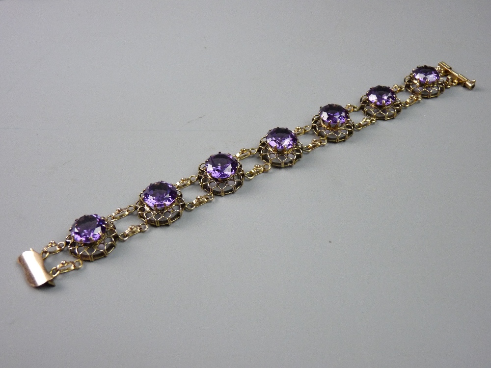 A BELIEVED FOURTEEN CARAT GOLD BRACELET having seven round cut amethysts all set in basket form