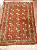 AN EASTERN WOOLLEN BOKHARA CARPET, hand knotted with central repeating pattern and wide multi-