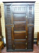 AN ANTIQUE OAK CORNER CUPBOARD with long centre door and short lower door on decorative brass hinges