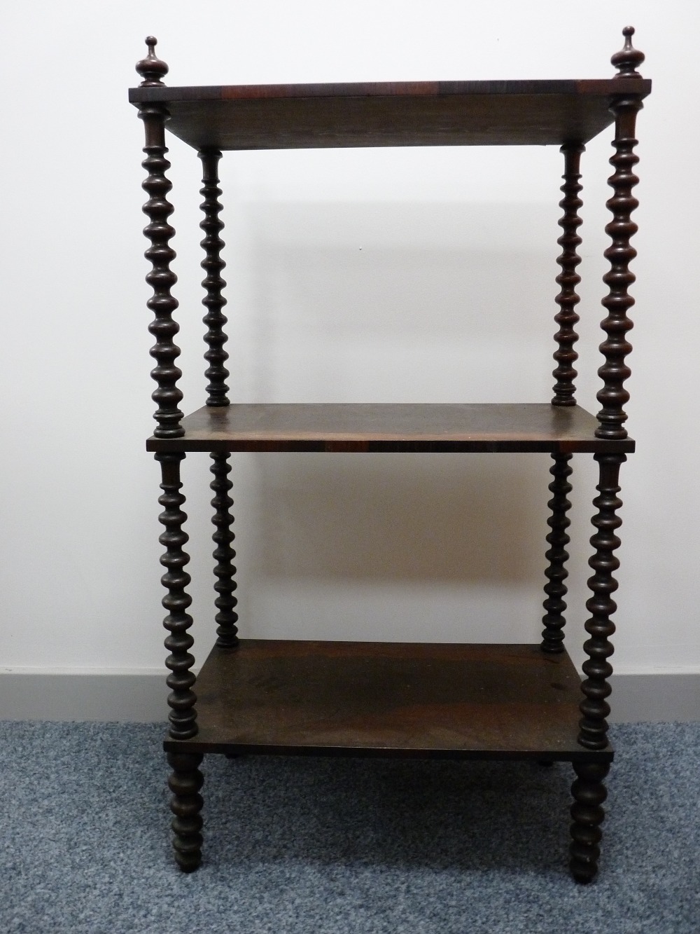 A VICTORIAN ROSEWOOD THREE TIER WHATNOT with finial corner caps and bobbin turned supports to the