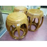 THREE CHINESE ROSEWOOD BARREL SHAPED STOOLS having circular tops with open panel sides, 45 cms