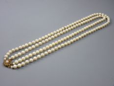 A DOUBLE NECKLACE OF CULTURED PEARLS with fine ruby and pearl decorated circular nine carat gold