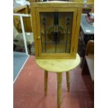 A PINE CRICKET TABLE and a leaded glass door wall cabinet, the 50 cms diameter top table on block