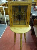 A PINE CRICKET TABLE and a leaded glass door wall cabinet, the 50 cms diameter top table on block