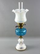 A VICTORIAN OIL LAMP with blue glass font supported on a brass mounted circular white pottery