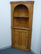 A STRIPPED PINE BARREL BACK STANDING CORNER CUPBOARD with cupboard base