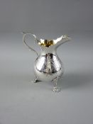 A BRIGHT CUT SILVER CREAM JUG with narrow neck and scroll handle on three claw supports, 3.8 troy