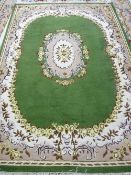 A GREEN GROUND INDIAN HAND KNOTTED WOOLLEN CARPET with cream and mushroom coloured border and