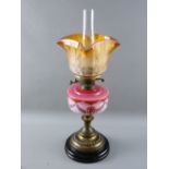 A VICTORIAN OIL LAMP with decorative pink milk glass font on a lacquered brass column and circular