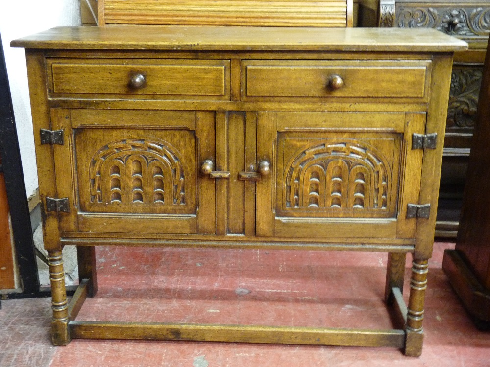 A SMALL REPRODUCTION OAK SIDEBOARD of two drawers and two cupboard doors with arched carved