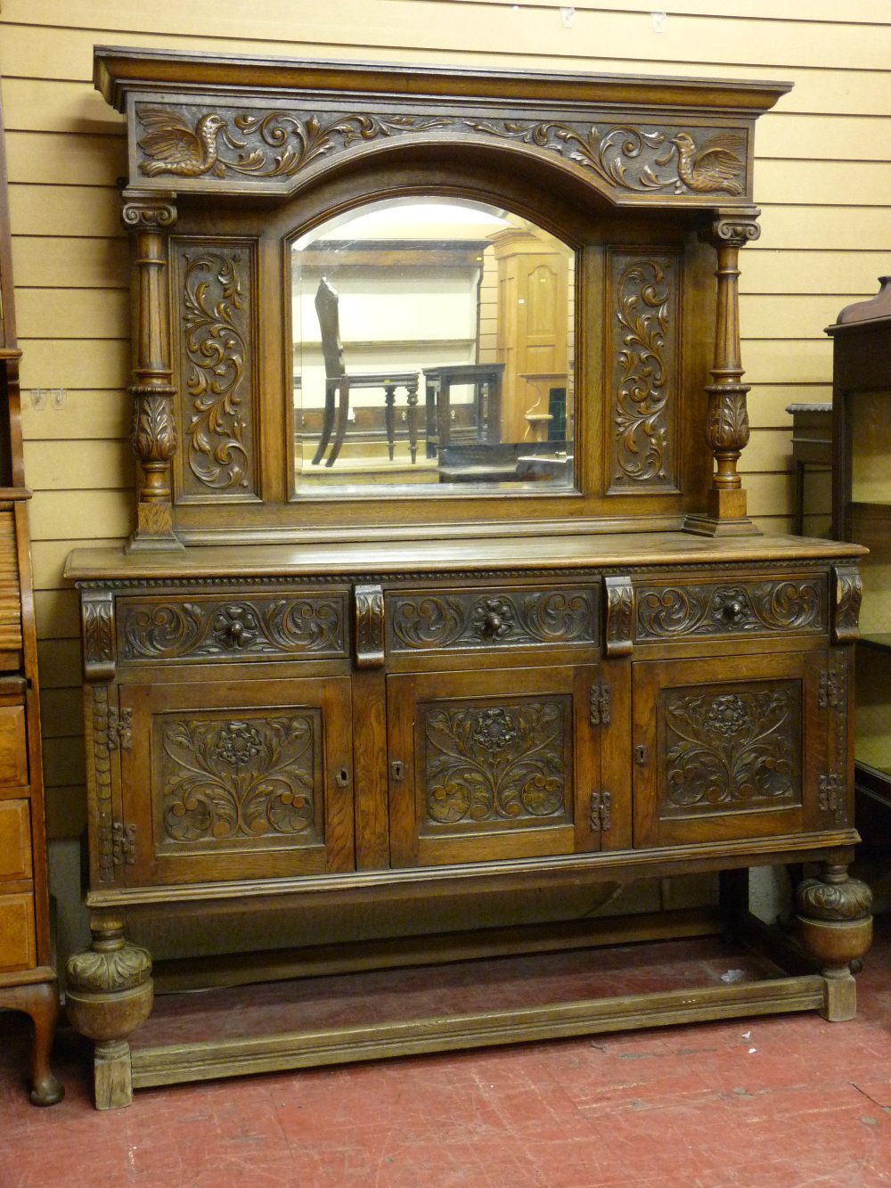 A CARVED OAK MIRRORBACK SIDEBOARD, the top section with arched top bevelled edge mirror, flanking