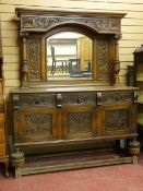 A CARVED OAK MIRRORBACK SIDEBOARD, the top section with arched top bevelled edge mirror, flanking