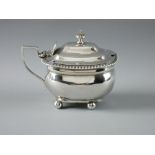 AN OBLONG SILVER MUSTARD POT, no liner, with hinged lid and on four ball feet, 5 troy ozs, London